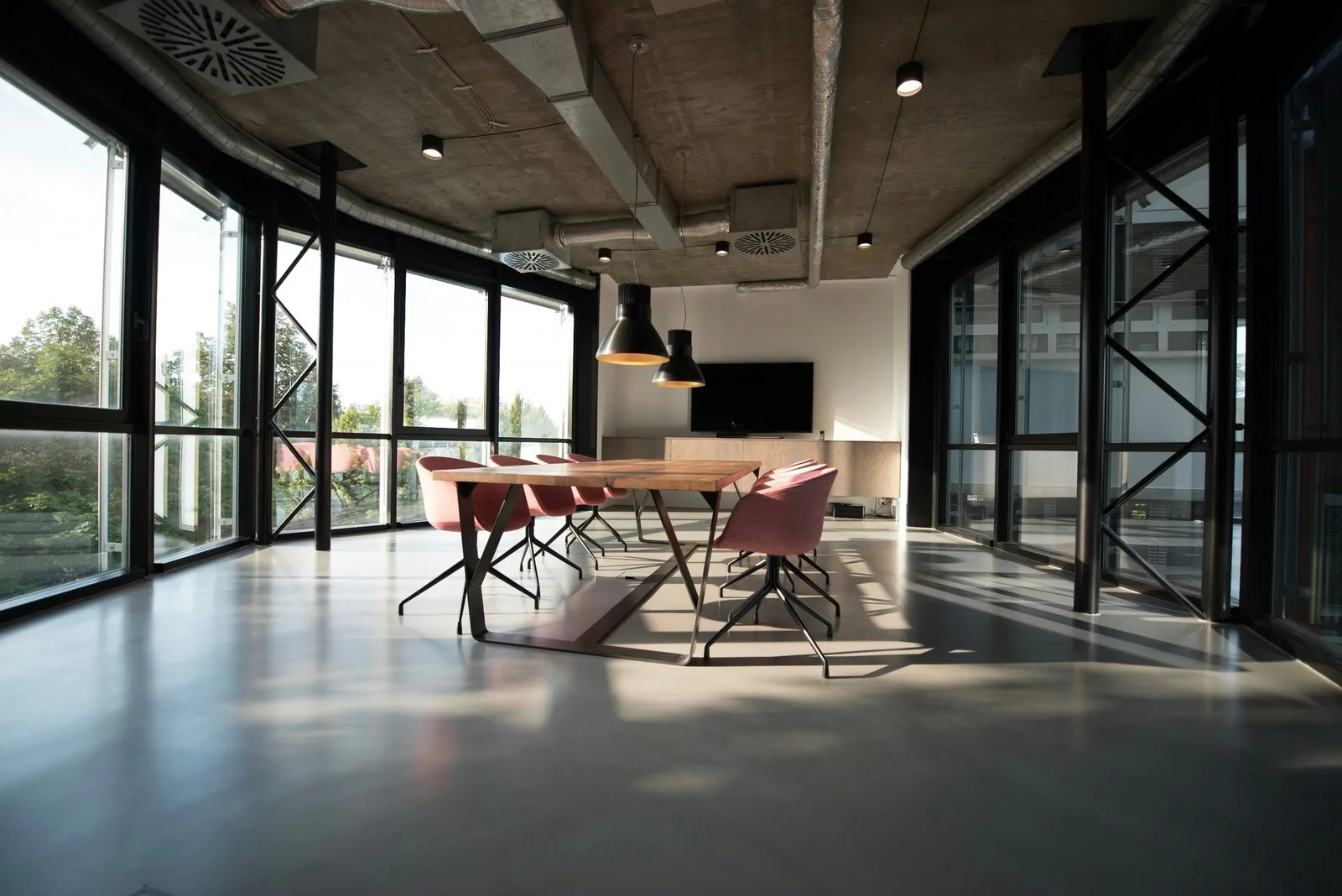 A light-filled meeting room with floor-to-ceiling windows and a timber table