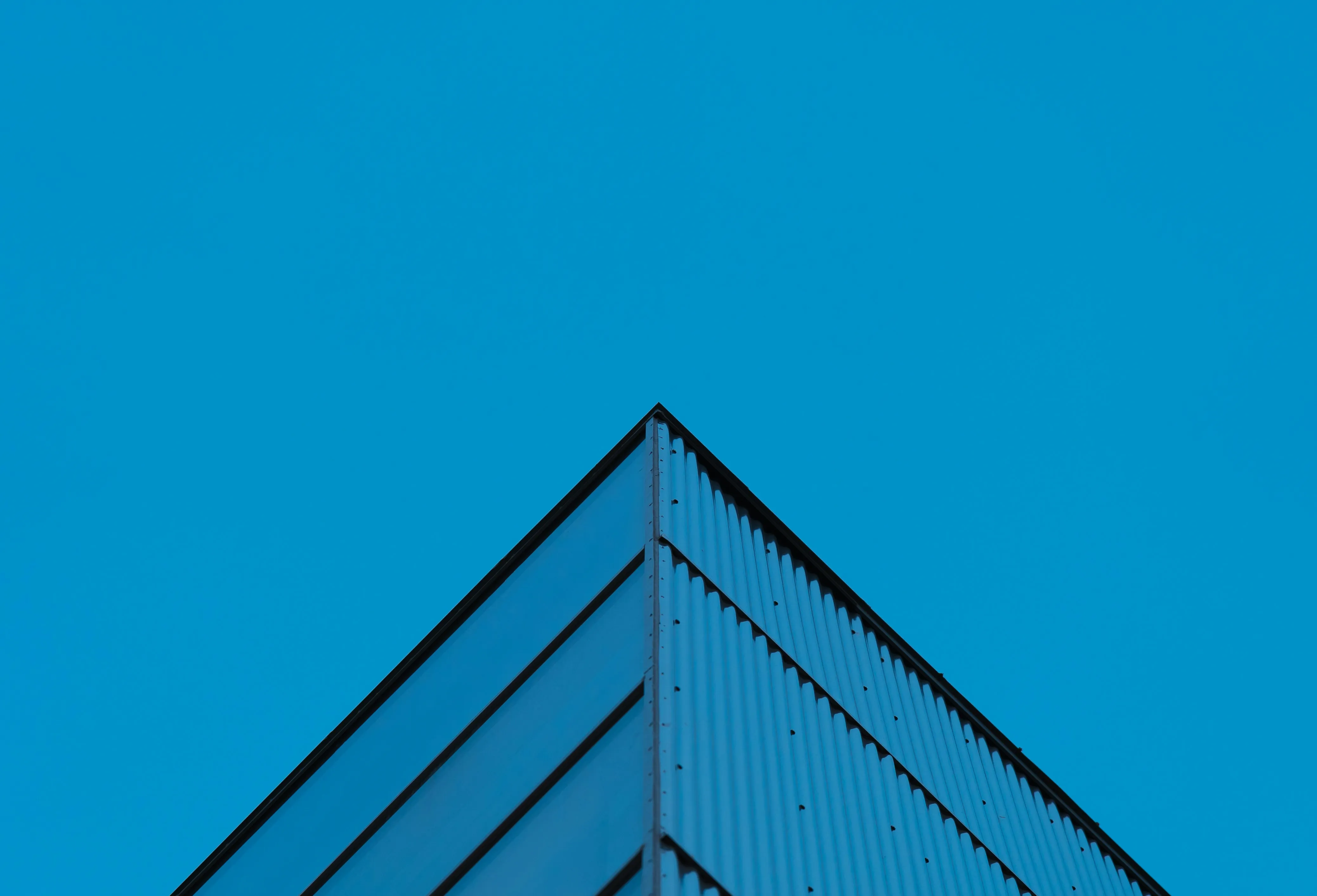 Modern building corner with clean geometric lines against a clear blue sky
